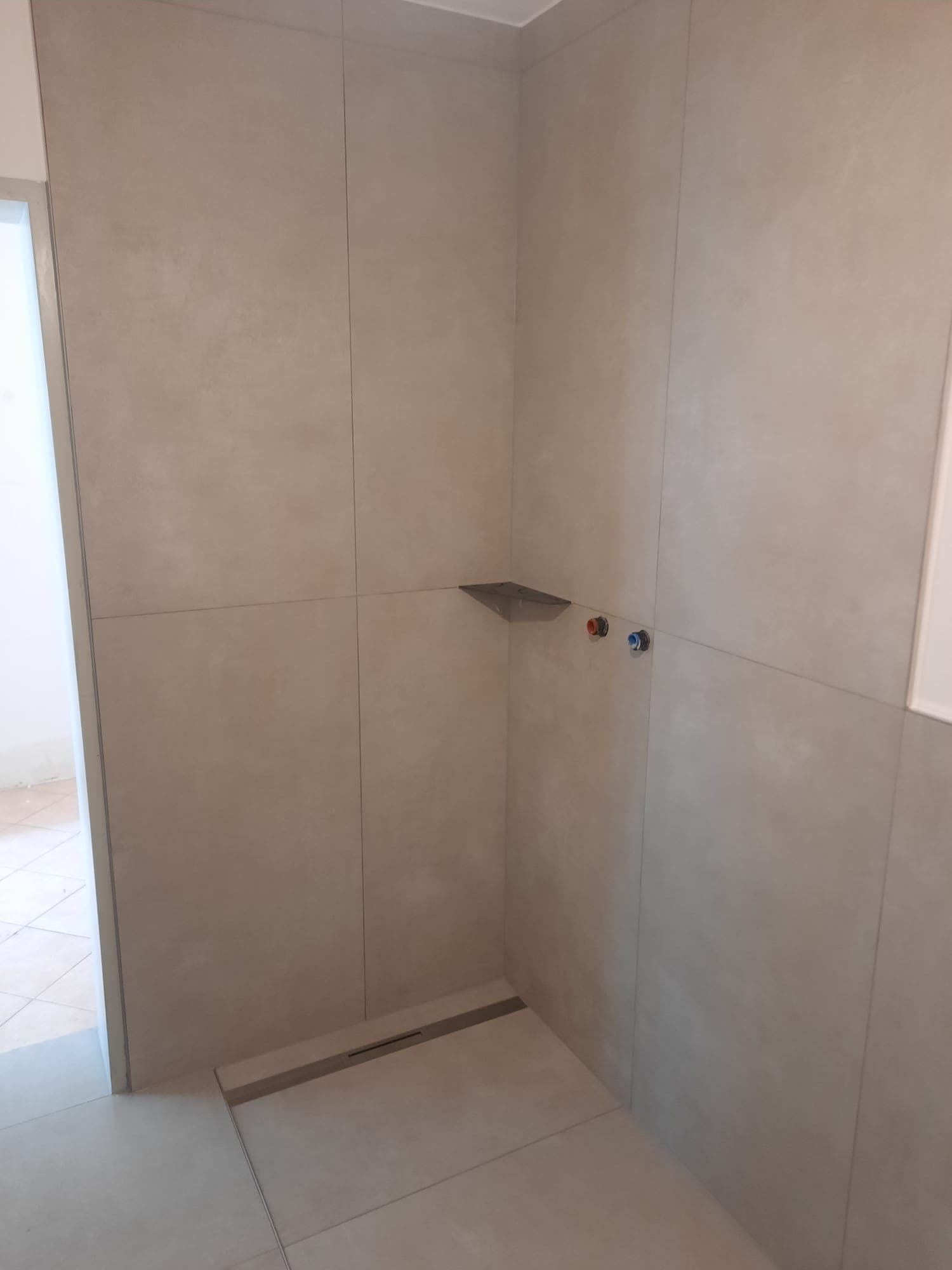 Professionell verlegte Eckbadewanne mit modernen Großformatfliesen in Schieferoptik
