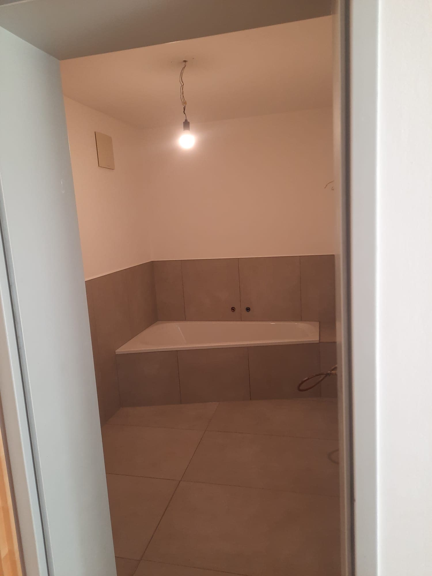 Professionell verlegte Eckbadewanne mit modernen Großformatfliesen in Schieferoptik