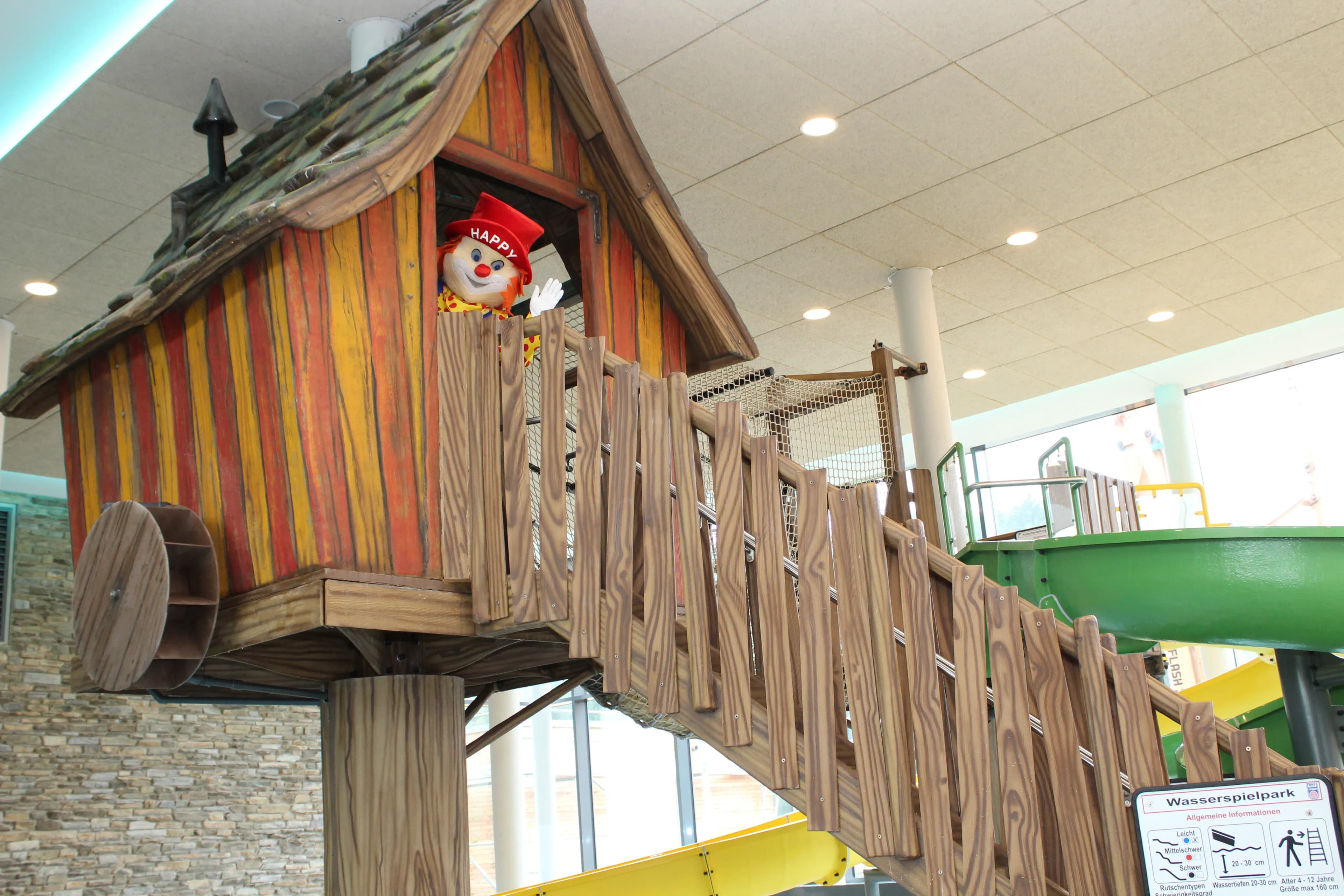 Glückliche Familie im Babyhotel Schreinerhof: Eltern entspannen im Wellnessbereich, während Kleinkinder spielerisch von pädagogisch geschultem Personal betreut werden – altersgerechtes Animationsprogramm für unvergesslichen Familienurlaub in Bayern.