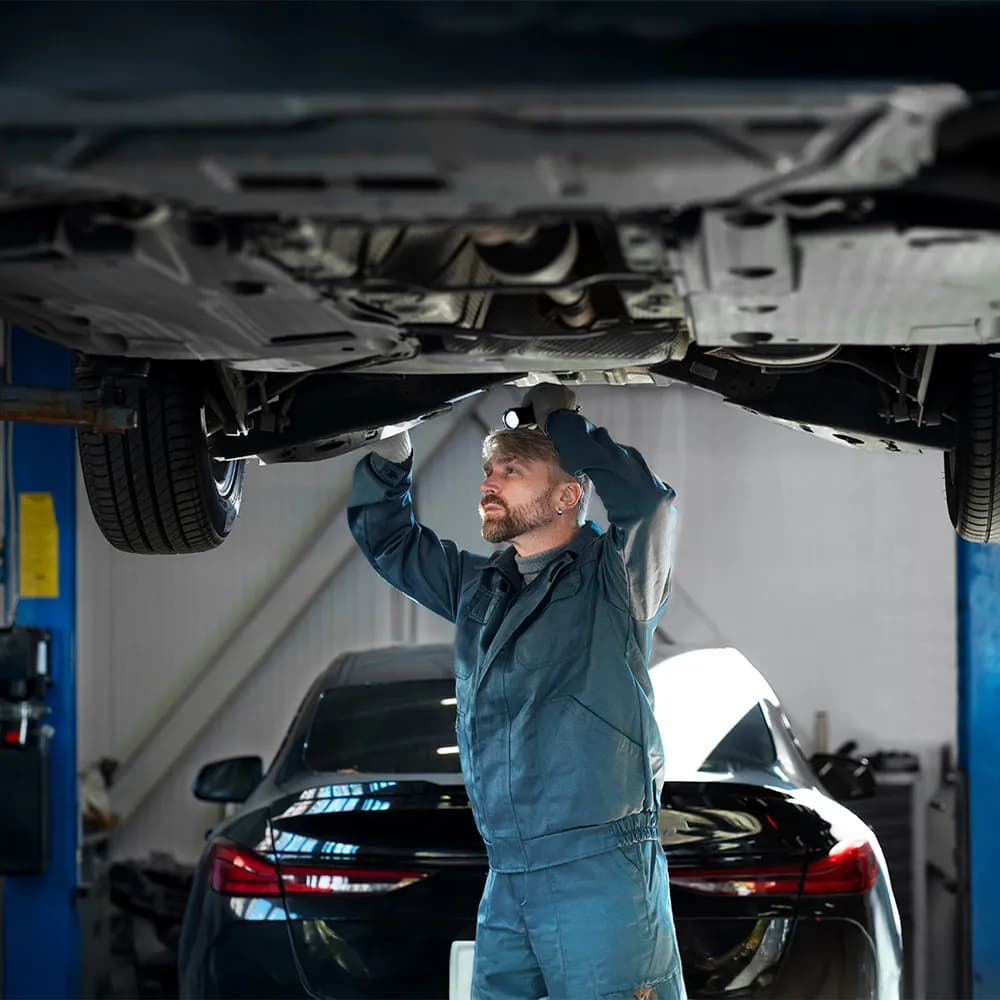 Ein Mechaniker bei der Arbeit unter dem Fahrzeug – regelmäßige Motorinnenreinigung kann teure Reparaturen vermeiden und für einen ruhigeren Motorlauf sorgen.